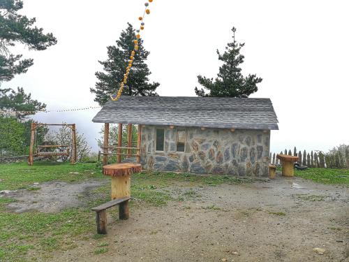 a small stone building with a bench in a field at Heshkili huts and cabins Svaneti in Keshkili