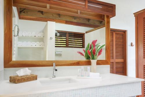 a bathroom with a sink and a mirror at Couples Swept Away in Negril
