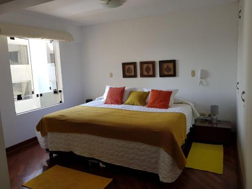 1 dormitorio con 1 cama grande con almohadas de color naranja y amarillo en Malecón, en Lima