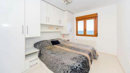 a bedroom with a bed and white cabinets and a window at La Mata Beach Apartment in La Mata