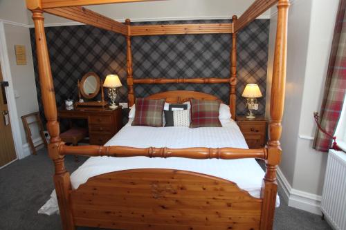 a bedroom with a wooden canopy bed with pillows at Kirkwood Guest House in Windermere