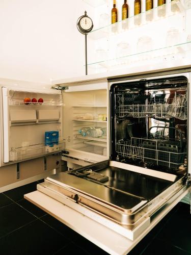 a kitchen with an open dishwasher with a dish rack at Casa das Barcas in Lourinhã