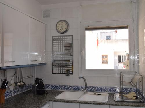 een keuken met een wastafel en een klok aan de muur bij Apartament platja in Platja  d'Aro