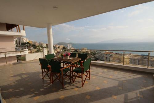 a table and chairs on a balcony with a view of the ocean at Nefeli Apartments in Sarandë