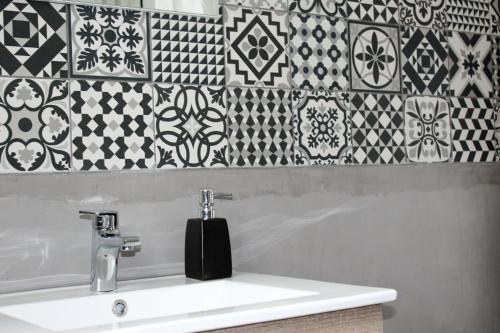 a bathroom sink with black and white tiles on the wall at Foz Surfcamp in Foz do Arelho