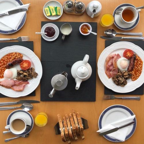 a table with plates of food and cups of coffee at Kirkwood Guest House in Windermere