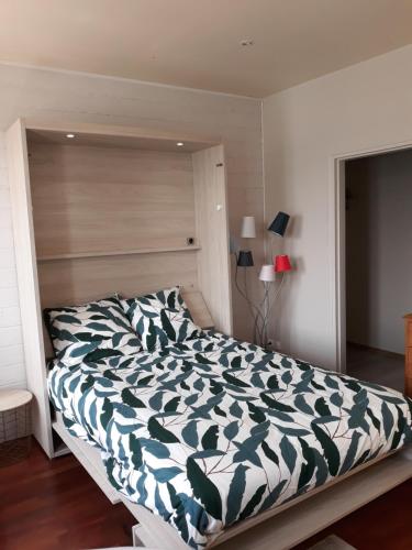 a bedroom with a bed with a green and white comforter at Le quai Sud in Fécamp