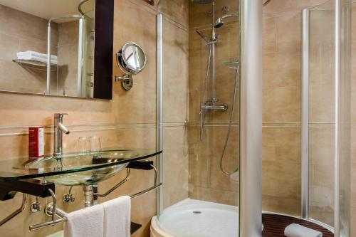 y baño con lavabo de cristal y ducha. en Exe Cunit Suites & Spa, en Cunit