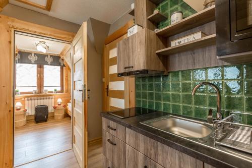 a kitchen with a sink and green tiles at Apartamenty U Studniara in Murzasichle
