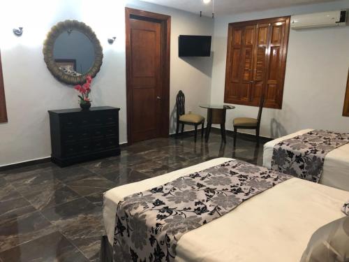 a hotel room with two beds and a mirror at Izamal Plaza in Izamal