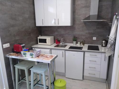 a kitchen with white cabinets and a counter with stools at Apartamento Cigüeña 1 in Zaragoza