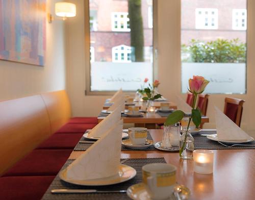a dining room with a table with napkins and candles at Hotel Cristobal in Hamburg