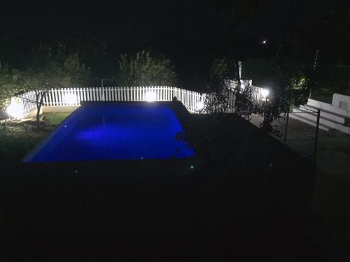 a blue swimming pool at night with a fence at I Colori degli Agrumi Holiday Home in Floridia