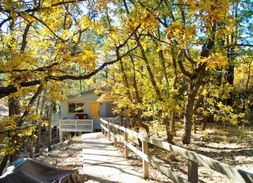 a house in the woods with a fence and trees at Cozy Mountain Home with Deck and Firepit-1 Mile from Downtown Flagstaff! in Flagstaff