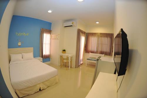 um quarto com uma cama, uma secretária e uma televisão em The Garden Living em Banguecoque