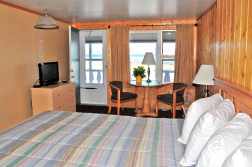 a bedroom with a bed and a table with a television at The Sunset Motel in Munising