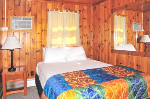 a bedroom with a bed in a room with wooden walls at The Sunset Motel in Munising