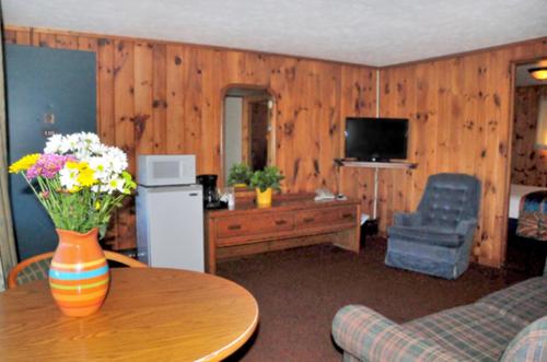 una sala de estar con un jarrón de flores sobre una mesa en The Sunset Motel, en Munising