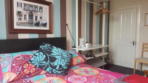a bedroom with a bed with colorful pillows on it at Angel Guesthouse in Tiverton