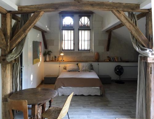 a bedroom with a bed and a table and windows at studio avec terrasse Abbaye d'Aiguevive in Faverolles-sur-Cher