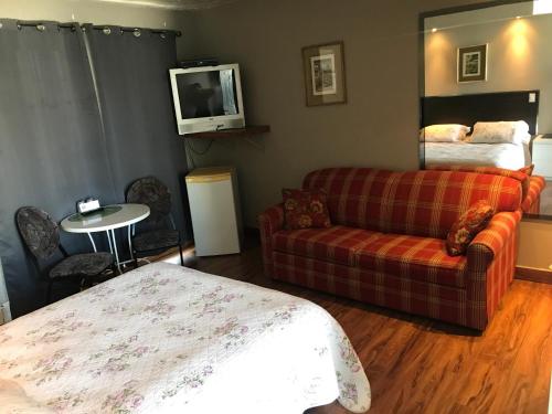 a bedroom with a bed and a couch and a tv at Motel la Siesta de Gascon in Terrebonne