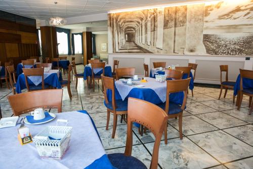 a dining room with tables and chairs and a painting at Hotel Ariston in Imperia