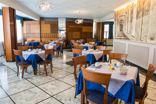 a dining room with tables and chairs and a chandelier at Hotel Ariston in Imperia