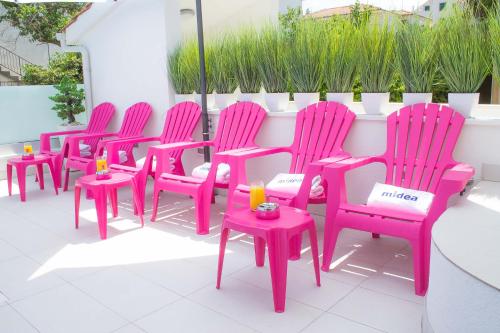 a row of pink chairs and tables on a patio at Villa Midea in Supetar