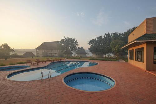 a large swimming pool with a brick patio at Victoria Forest Resort in Kalangala