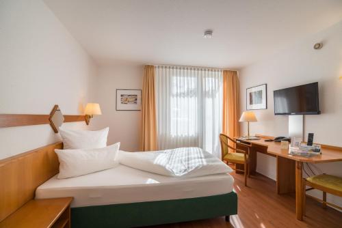 a hotel room with a bed and a desk at Airporthotel Residenz Steinenbronn in Steinenbronn