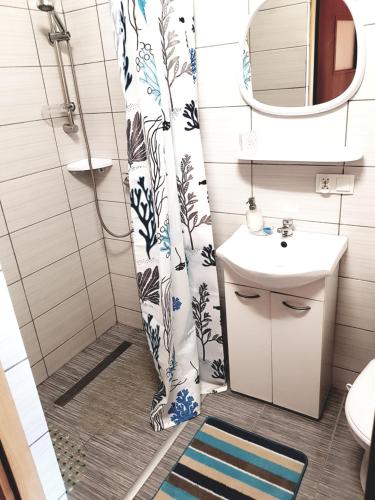 a bathroom with a shower curtain and a sink at domki letniskowe "U EWKI" in Sarbinowo