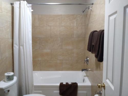 ein Badezimmer mit einer Badewanne, einem WC und einem Waschbecken in der Unterkunft Aries Motel in Edson