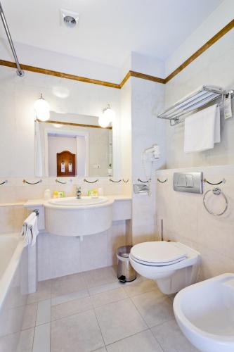 a bathroom with a sink and a toilet and a tub at Qubus Hotel Wrocław in Wrocław