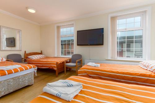 ブラックプールにあるBrecks Hotelのベッド3台、薄型テレビが備わる客室です。