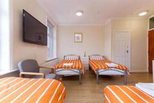 a room with three beds and a flat screen tv at Brecks Hotel in Blackpool