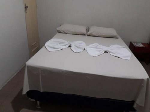 a bed with white sheets and bows on it at Hotel Danubio in Itabaiana
