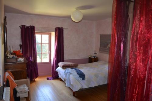 1 dormitorio con 1 cama con cortinas rojas y ventana en Chez Germaine, en Les Granges-Gontardes