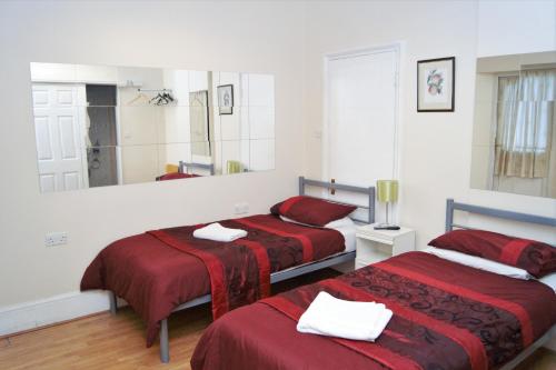 een slaapkamer met 2 bedden met rode lakens en een spiegel bij The Dharma Lodge in Enfield