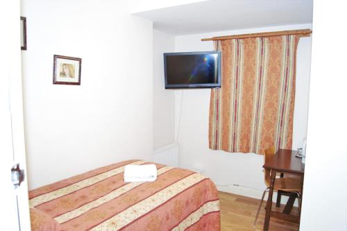 a hotel room with a bed and a television on the wall at The Dharma Lodge in Enfield
