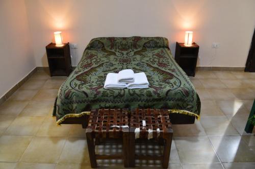 a bed with a green blanket and a table with two candles at El Refugio in Yala