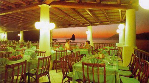 un restaurante con mesas verdes y sillas y gente en él en Hotel Conti, en Vulcano