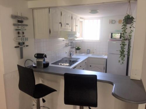 uma cozinha com armários brancos e um balcão preto em Mer et Soleil em La Ciotat