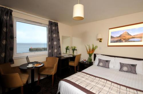 Habitación de hotel con cama, mesa y ventana en Dunollie Hotel ‘A Bespoke Hotel’, en Broadford