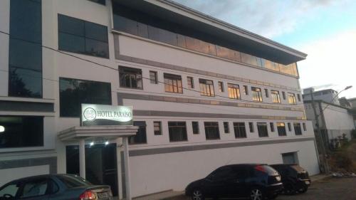 a building with two cars parked in front of it at Hotel & Restaurante Paraíso - By Up Hotel in Ponte Nova