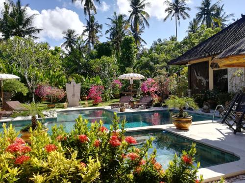 a pool at a resort with flowers and palm trees at Villa Gusmania in Candidasa