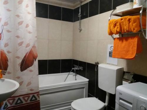 a bathroom with a toilet and a sink and a tub at The Orange Apartment in Skopje