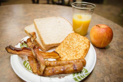 a plate of breakfast food with bacon and toast and an apple at Super 8 by Wyndham Drayton Valley in Drayton Valley