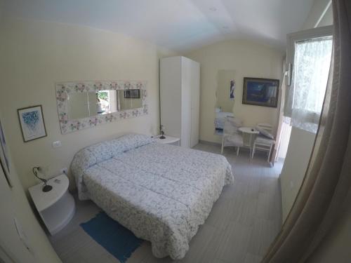 a white bedroom with a bed and a desk at hotel la rondinella in Ischia