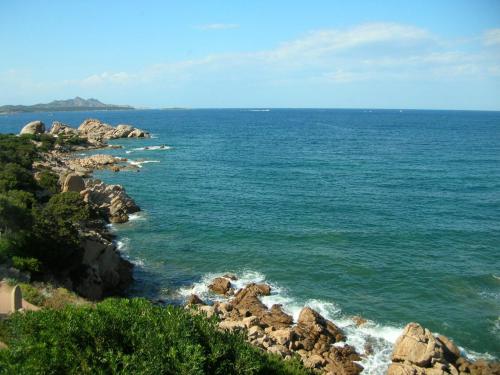 a large body of water with rocks and the ocean at Club Hotel Baja Sardinia in Baja Sardinia