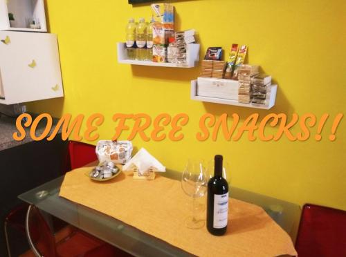 a table with a bottle of wine and a sign that says some free snacks at Siracusa Ortigia by Duomo in Siracusa